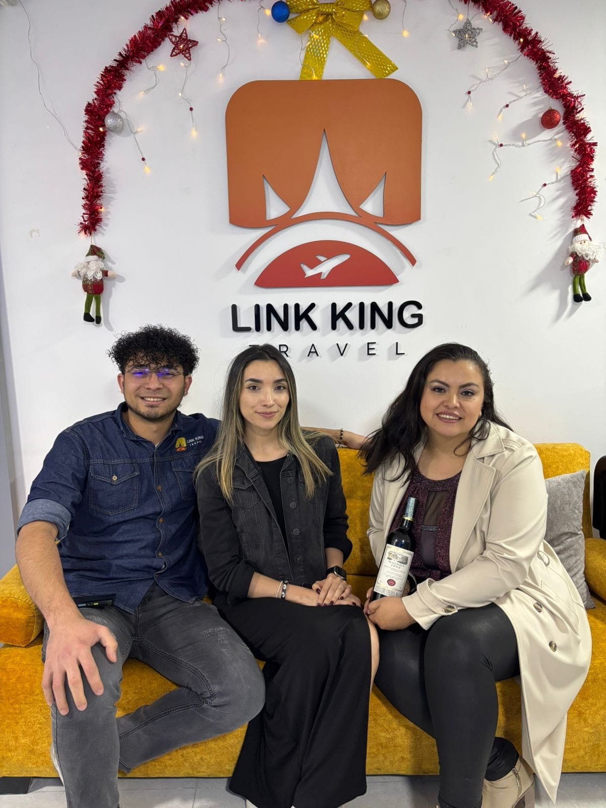 Clientes celebrando su viaje con una botella de vino en la oficina de Link King Travel